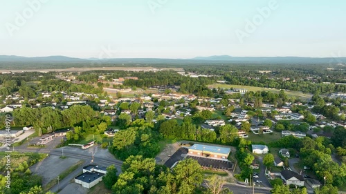Aerial view of residential neighborhoods in Plattsburgh, New York, with Adirondack Mountains, green landscapes, and golden evening summer light.