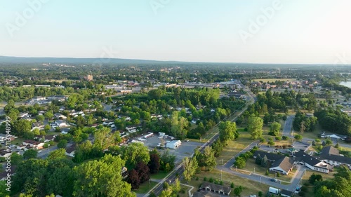 Aerial view of residential neighborhoods in Plattsburgh, New York, with Adirondack Mountains, green landscapes, and golden evening summer light.