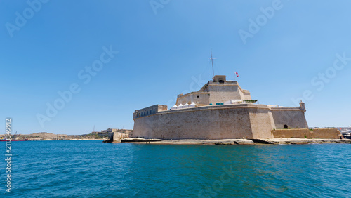 Obraz na płótnie Massive limestone fortification walls and bastions rising above deep blue waters