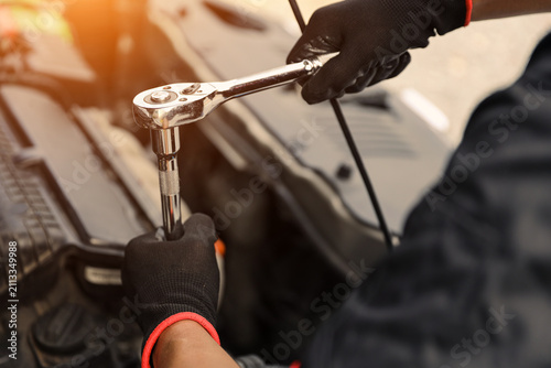 Car care maintenance servicing technician or auto mechanic holding wrench for fix service repairing change spare part engine problem or insurance support or range of car check or training workshop.