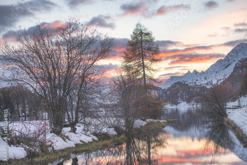 Snowy Winter Landscape with Colorful Sunset over Mountain Lake
