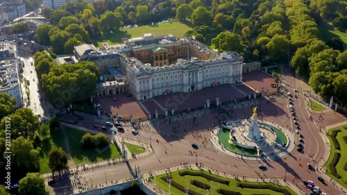 Aerial drone view of Buckingham Palace royal residence, the Victoria Memorial and tourists at the palace gates near St James Park in Westminster, London, United Kingdom, on a sunny day.