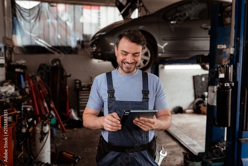 Mechanic checks tablet while working in auto repair shop