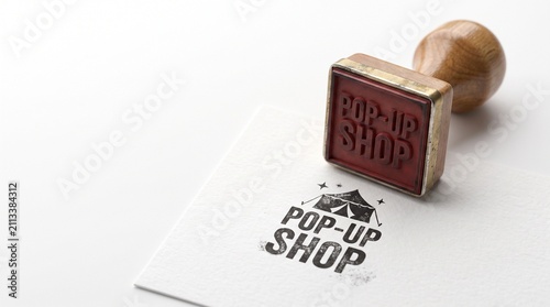 Vintage wooden rubber stamp with Pop-Up Shop text, retail branding concept on white paper, temporary store marketing tool