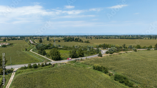 Bild auf Leinwand Rural Intersection in Green Fields: An aerial view captures a crossroads connecting vast expanses of lush green agricultural fields under a clear blue sky
