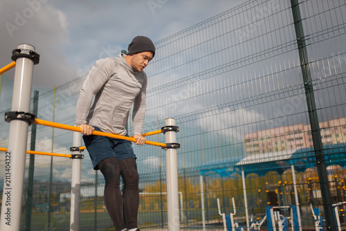 Obraz na plátně Athletic young man doing parallel bar dips during street workout at outdoor spor