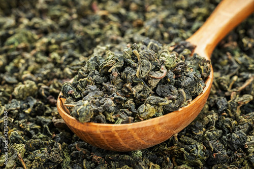 Tieguanyin loose leaf in wooden spoon on solid background