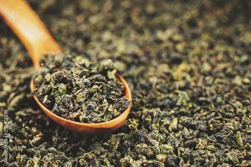 Premium dried oolong tea scoop on minimal solid background