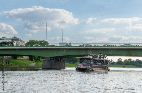 Foto Contemporary sightseeing catamaran navigating beneath a bridge across the Vistula River in Krakow, Poland