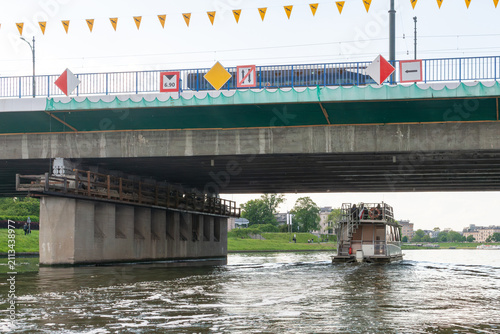 Konstfotografi Tourist excursion boat navigating beneath a major road bridge across the Vistula River in Krakow, Poland