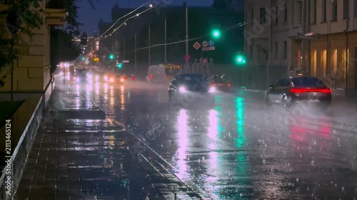 
Night city scene during heavy rain, slow motion raindrops and water streams, reflections of lights on wet asphalt, atmospheric weather and dramatic mood,