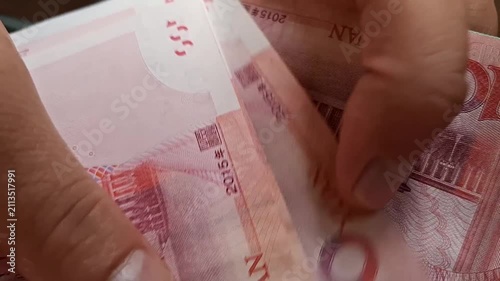 Person counts one hundred Chinese yuan banknotes with hands in a close-up shot. chinese currency exchange, cash payment transaction, asian financial economy.
