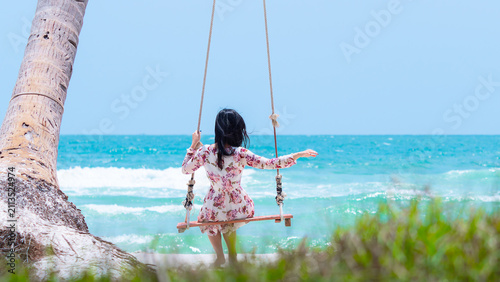 Girl on the swings on the paradise beach with sea