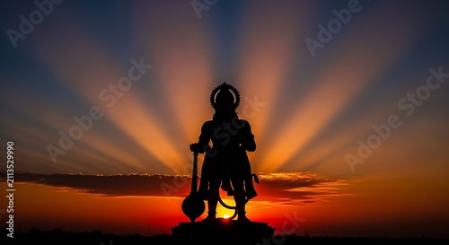 Silhouette of Lord Hanuman statue against a vibrant sunset sky in India