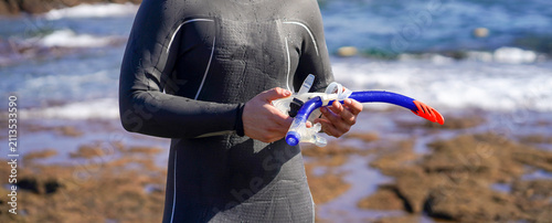 Foto A man holds a mask and snorkeling tube for swimming in the ocean on a sunny day