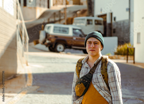 A man is wallking in a town on a sunny day, a tourist enjoys his leasure time walking on the streets of a city.