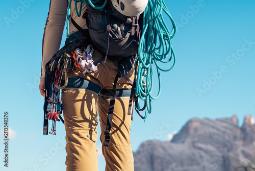 Foto Mountaineering gear with carabiners, ropes, belay devices on a young man closeup