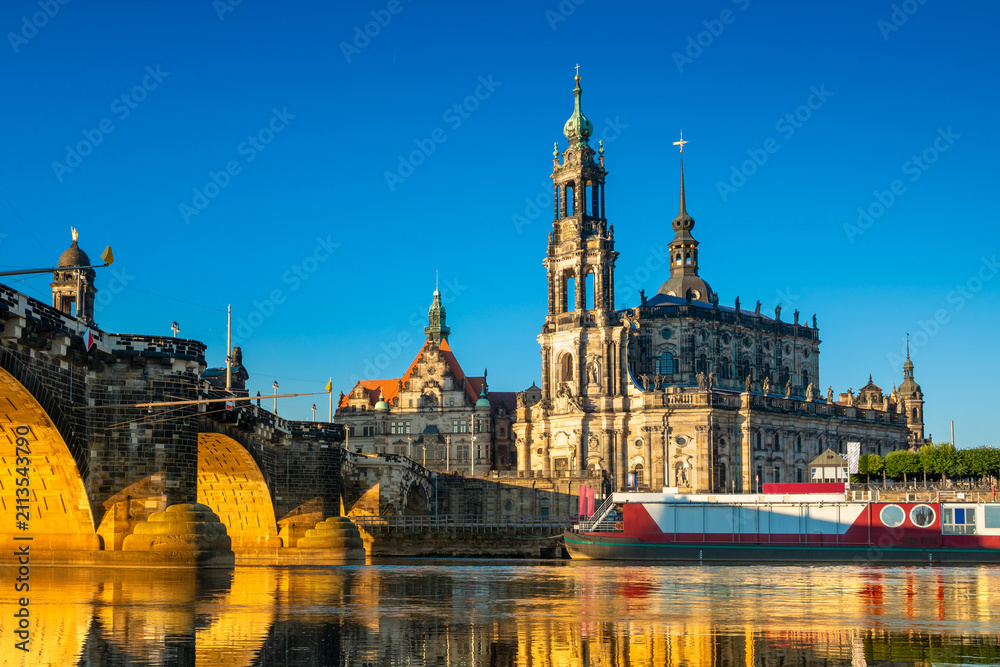 Fototapeta premium Augustus Bridge and Cathedral of the Holy Trinity or Hofkirche with reflections in the river Elbe. Dresden, Saxony, Germany
