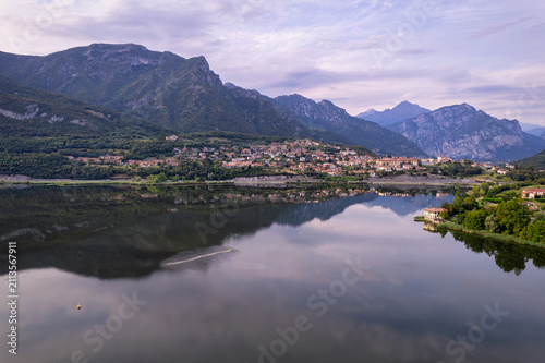 Fotografía Calm mountain lake reflecting Alpine peaks and lakeside village at dawn, Brianza