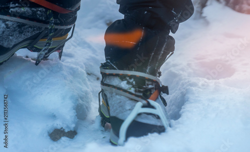 Foto Mountaineering boots with crampons closeup, a winter hiking on a snowy trail