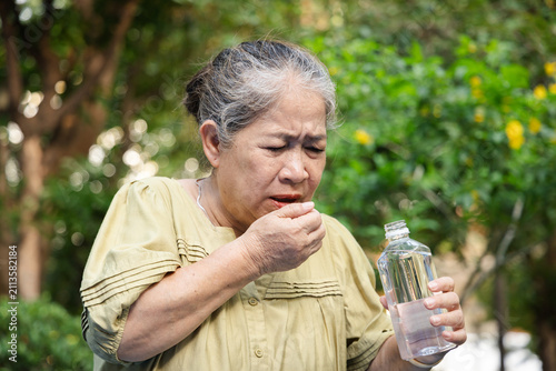 Photos elderly asian senior woman gasping and coughing after choking on bottled water o
