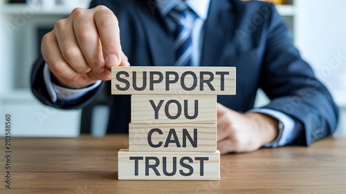 Professional hand carefully stacking wooden blocks that read SUPPORT YOU CAN TRUST