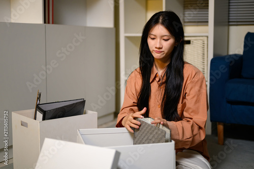 Foto Young Asian Businesswoman Packing Personal Belongings in Box After Resignation f