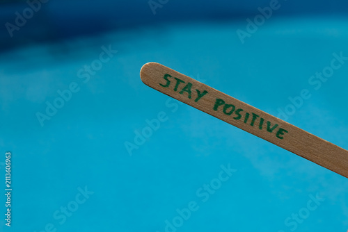 Canvastavla Woman holding a popsicle stick with the words Stay positive against a blue swimming pool background, creating an uplifting summer lifestyle concept about optimism, happiness and positive thinking
