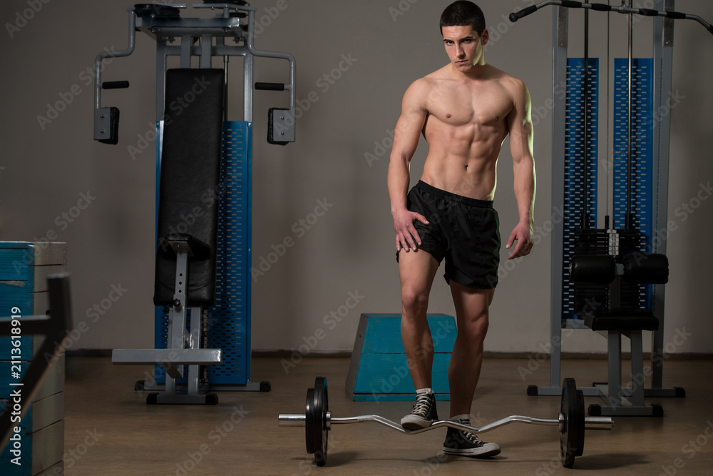 Fototapeta premium Young Muscular Men Standing By The Barbell