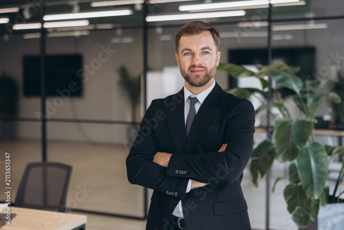 Businessman presenting a confident and professional demeanor  standing with folded arms in a bright corporate office interior