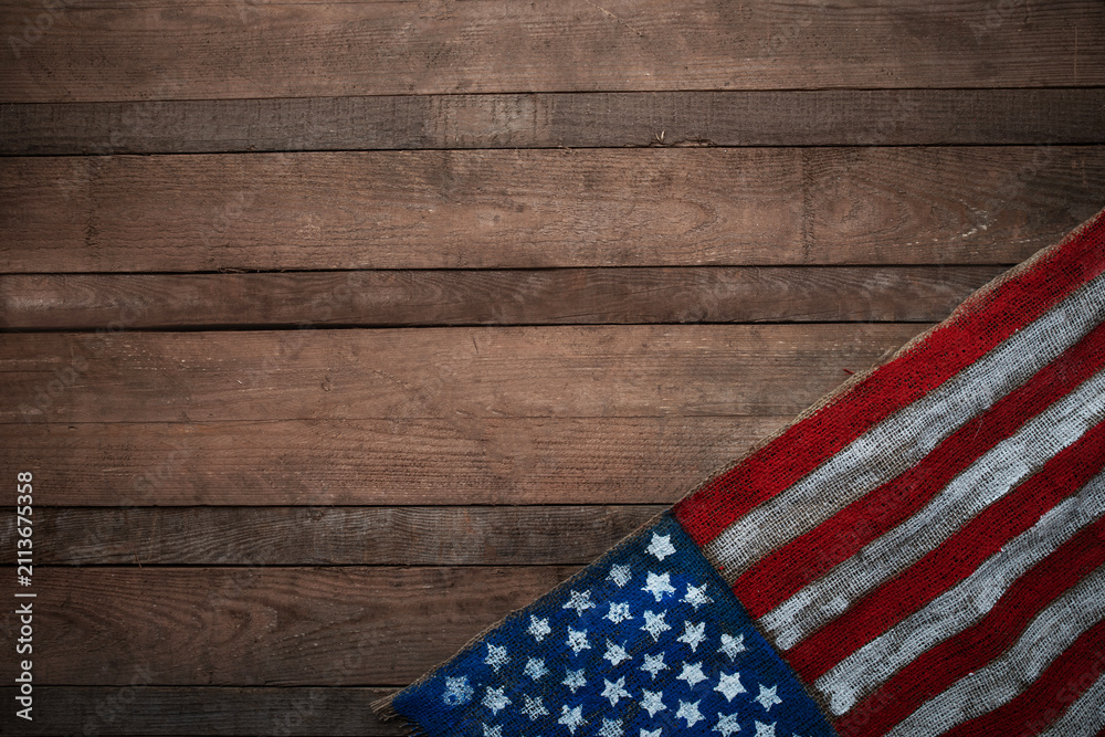 Obraz premium USA flag on burlap fabric over wooden wall background, rustic patriotic texture with copy space for national holidays, Independence, Flag and Constitution Day design.