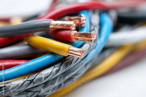 Macro view of colorful electrical wire bundles with stripped copper conductors. Red, blue, yellow power cables for electricity installation, network communication hardware. Electric, power engineering