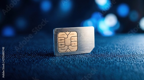 Macro close up of single mobile phone sim card with gold electronic chip on dark textured surface with blue bokeh lights in background for cellular technology concept.