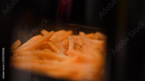 French fries cooking inside an air fryer. Crispy potato snack being prepared in modern kitchen appliance. Healthy fat free fried food culinary process for dining and fast food meal.