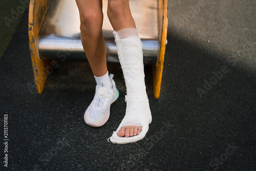 Canvastavla Child with broken leg in cast sitting on playground slide