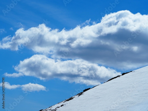 Panoramic view of the snowy Valle de Bujaruelo in the Spanish Pyrenees, featuring towering snow-capped mountain peaks and a deep blue sky.