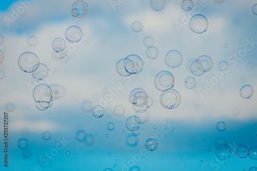 фотографія Transparent soap bubbles floating against a blue sky with soft clouds, creating