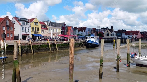 Historic harbor of Husum with an boat during the incoming tide, surrounded by the colorful old town and North Sea tidal waters.