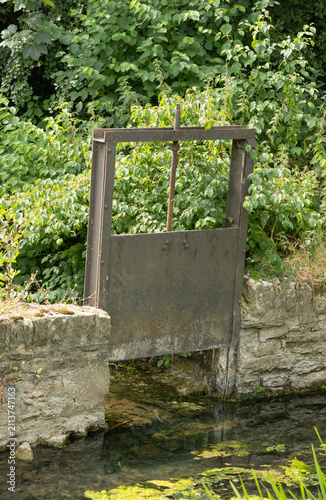Bild auf Leinwand Historic steel sluice gate spanning a river channel, designed to control water levels and regulate flow