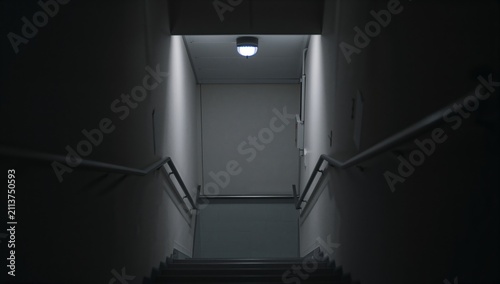 Steps Leading Down to a Door With Light Casting Shadows in a Dim Space