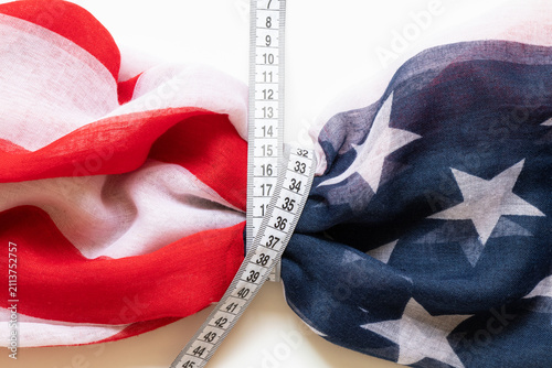 Картината върху платно The US flag and tape measure on a white background as a symbol of weight control
