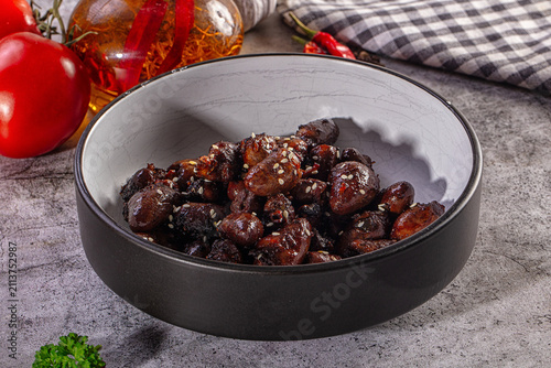 Obraz na płótnie Appetizing glazed chicken hearts with sesame seeds in a rustic bowl