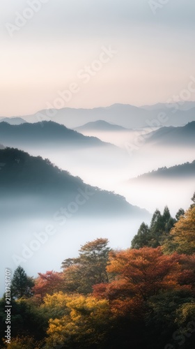 Serene mountainous landscape bathed in soft morning fog with vibrant autumn foliage creating a picturesque scene of tranquility and natural beauty
