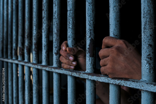 Obraz na plátně Close up of prisoner hands holding rusty iron bars, behind bars concept of impri