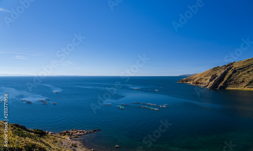 Foto Wide scenic view over Lake Titicaca from a rocky shoreline, showing floating aqu
