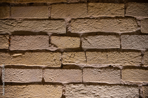 A close-up view of an old, weathered brick wall with visible mortar lines and subtle color variations