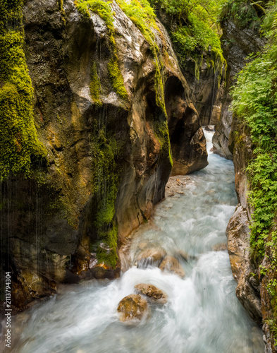 Canvas Print Cascading alpine river with motion blur silk effect through narrow green canyon