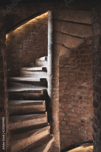 People walk up and down the spiral staircase inside White Tower in Hradec Kralove. The old stone walls and lighting create a unique atmosphere. It is a popular place for visitors.