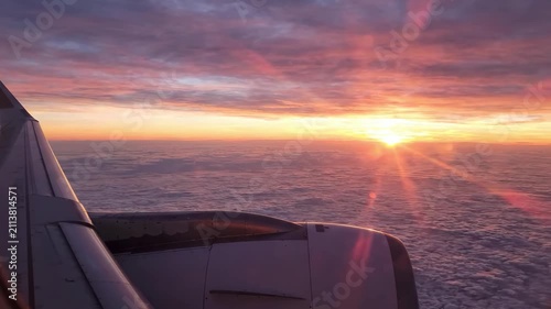 Stunning Airplane Window View of Golden Sunset Above Clouds During a Peaceful Flight.
