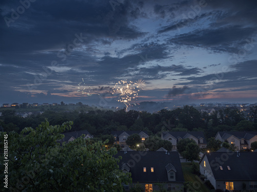 4th of July fireworks exploding in twilight sky over suburban Pennsylvania houses with copyspace